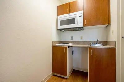 a small kitchen with a sink and a microwave at HomeTowne Studios by Red Roof Denver - Lakewood West in Lakewood