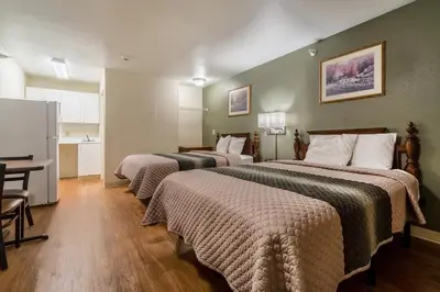 a hotel room with two beds and a flat screen tv at HomeTowne Studios by Red Roof Denver - Lakewood West in Lakewood