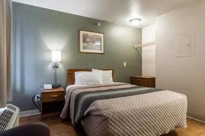a bedroom with a bed and a green wall at HomeTowne Studios by Red Roof Denver - Lakewood West in Lakewood