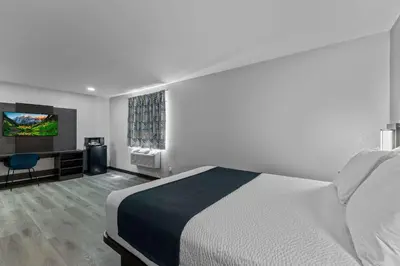 a bedroom with a bed and a desk and a television at Motel 6 Brighton CO Denver Northeast in Brighton