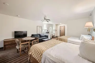 a hotel room with two beds and a living room at Travelodge by Wyndham Longmont in Longmont