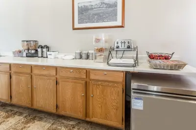 a kitchen with wooden cabinets and a counter top at Travelodge by Wyndham Longmont in Longmont