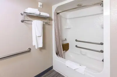 a bathroom with a shower with white towels at Motel 6-Fort Lupton, CO in Fort Lupton