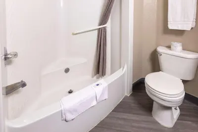 a white bathroom with a toilet and a bath tub at Motel 6-Fort Lupton, CO in Fort Lupton