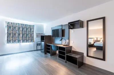 a room with a desk and a mirror and a bed at Motel 6-Fort Lupton, CO in Fort Lupton