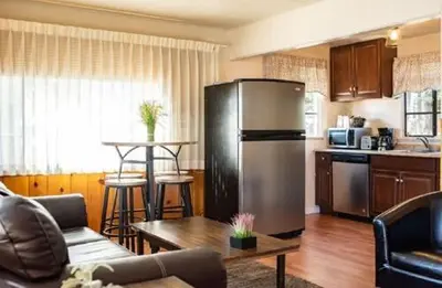 a kitchen with a stainless steel refrigerator in a living room at Alpine Trail Ridge Inn in Estes Park