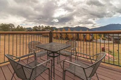 a table and chairs on a deck with a view at Blue Door Inn in Estes Park