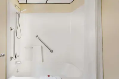 a white bathroom with a shower and a sink at Travelodge by Wyndham Loveland/Fort Collins Area in Loveland