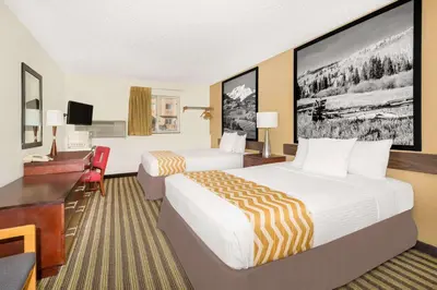 a hotel room with two beds and a desk at Travelodge by Wyndham Loveland/Fort Collins Area in Loveland