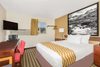 a hotel room with a bed and a desk and a computer at Travelodge by Wyndham Loveland/Fort Collins Area in Loveland