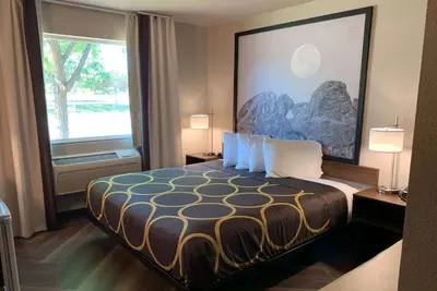 a hotel room with a bed and a large window at Super 8 by Wyndham Greeley in Greeley