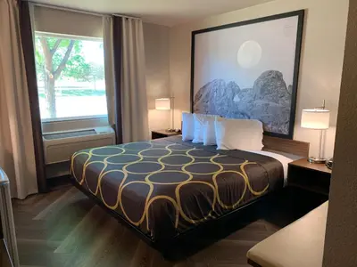 a hotel room with a bed and a large window at Super 8 by Wyndham Greeley in Greeley
