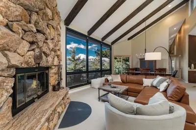a living room with a large stone fireplace at The Cedars Luxury Home At Windcliff Home in Estes Park