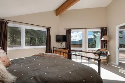 a bedroom with a bed and windows and a television at The Cedars Luxury Home At Windcliff Home in Estes Park