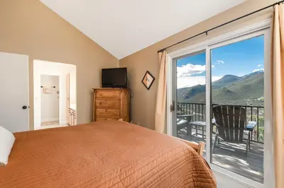 a bedroom with a bed and a balcony with a view at The Cedars Luxury Home At Windcliff Home in Estes Park