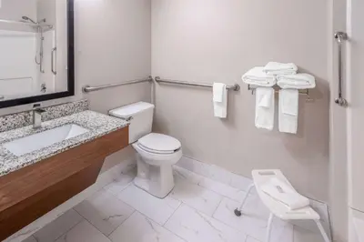 a bathroom with a toilet and a sink with towels at Days Inn & Suites by Wyndham Greeley in Greeley