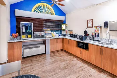 a large kitchen with wooden cabinets and a ceiling fan at Days Inn & Suites by Wyndham Greeley in Greeley