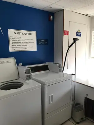 a guest laundry room with a washing machine and a lamp at Days Inn & Suites by Wyndham Greeley in Greeley