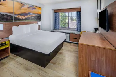 a hotel room with a bed and a flat screen tv at Days Inn & Suites by Wyndham Greeley in Greeley