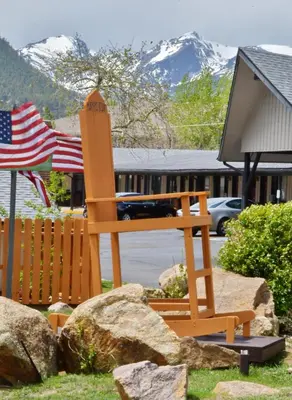 a wooden chair sitting in a yard with an american flag at Murphy's Resort in Estes Park