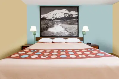 a bedroom with a large bed with a mountain painting on the wall at Super 8 by Wyndham Dillon/Breckenridge Area in Dillon