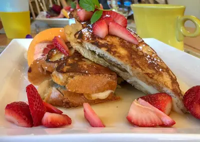 two pieces of french toast with strawberries on a plate at Riversong Inn Retreat in Estes Park