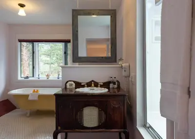 a bathroom with a sink and a tub and a mirror at Riversong Inn Retreat in Estes Park