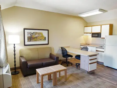 a living room with a couch and a desk and a kitchen at Extended Stay America Select Suites - Denver - Tech Center South - Greenwood Village in Centennial