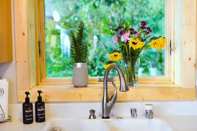 a kitchen sink with a window with flowers on it at Nederland Getaway Home in Nederland