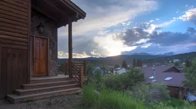 a cabin with a porch with a sunset in the background at Nederland Getaway Home in Nederland