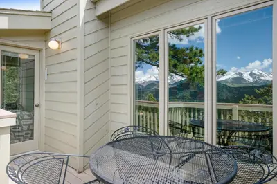 a table and chairs on a balcony with a view of mountains at Deering Crest in Estes Park