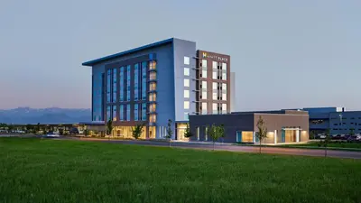 a large blue building with a green field in front of it at Hyatt Place Pena Station/Denver Airport in Denver