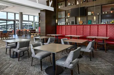 a restaurant with tables and chairs and a red wall at Hyatt Place Pena Station/Denver Airport in Denver