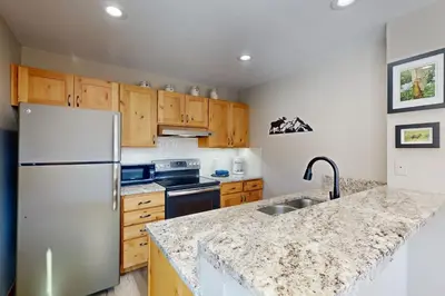 a kitchen with wooden cabinets and a white refrigerator at Watch Hill 216 in Silverthorne