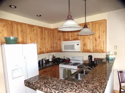 a kitchen with wooden cabinets and a white refrigerator at Anemone Townhome 3 bed 3 bath HTAT in Silverthorne