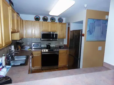 a kitchen with wooden cabinets and a black refrigerator at Forest Park 3 bed 4 Bath Twnhm HTJM in Silverthorne