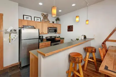 a kitchen with a stainless steel refrigerator and two bar stools at Arapahoe Lodge 1 Bed 2 Bath ALJD in Keystone