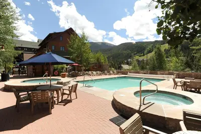 a swimming pool with a table and chairs and an umbrella at Arapahoe Lodge 1 Bed 1 Bath ALJP in Keystone