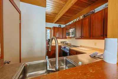 a kitchen with a stainless steel sink and wooden cabinets at Tennis Townhome 2 Bd 25 Ba TTMR in Keystone