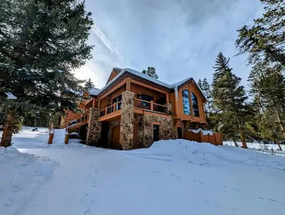 a log home in the snow in the woods at Goldenrod Home 7 by SummitCove Lodging in Keystone