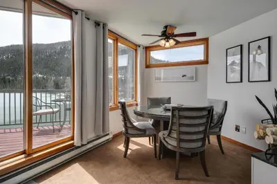 a dining room with a table and chairs and a balcony at Lakeside 1481 by SummitCove Lodging in Keystone