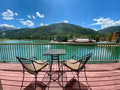 two chairs and a table on a deck overlooking a lake at Lakeside 1481 by SummitCove Lodging in Keystone