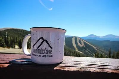 a coffee mug sitting on a table with mountains in the background at Alders 854 By SummitCove Lodging in Keystone