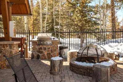 a patio with a stone grill and a fire pit at Seasons 1850 in Keystone