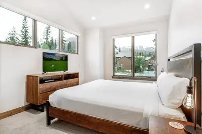 a bedroom with a bed and a tv and windows at Treehouse Village 323 in Silverthorne