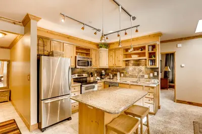 a kitchen with wooden cabinets and a stainless steel refrigerator at Spacious 1Br Condo-River Run Village-Hot Tub & Kids Ski Free Condo in Keystone