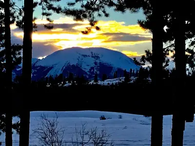 a snow covered mountain with a sunset in the background at Spacious And Modern 2Br Premier- The Pines- Kids Ski Free Condo in Keystone