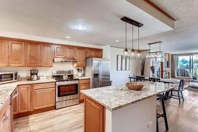 a kitchen with wooden cabinets and a large island at Spacious And Modern 2Br Premier- The Pines- Kids Ski Free Condo in Keystone