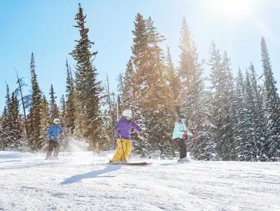 three people are skiing down a snow covered slope at Heart Of River Run & Spacious 2Br Premier Condo in Keystone