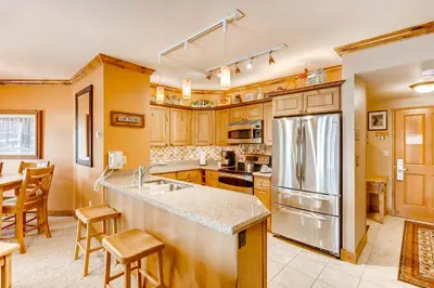 a kitchen with wooden cabinets and a stainless steel refrigerator at Heart Of River Run & Spacious 2Br Premier Condo in Keystone